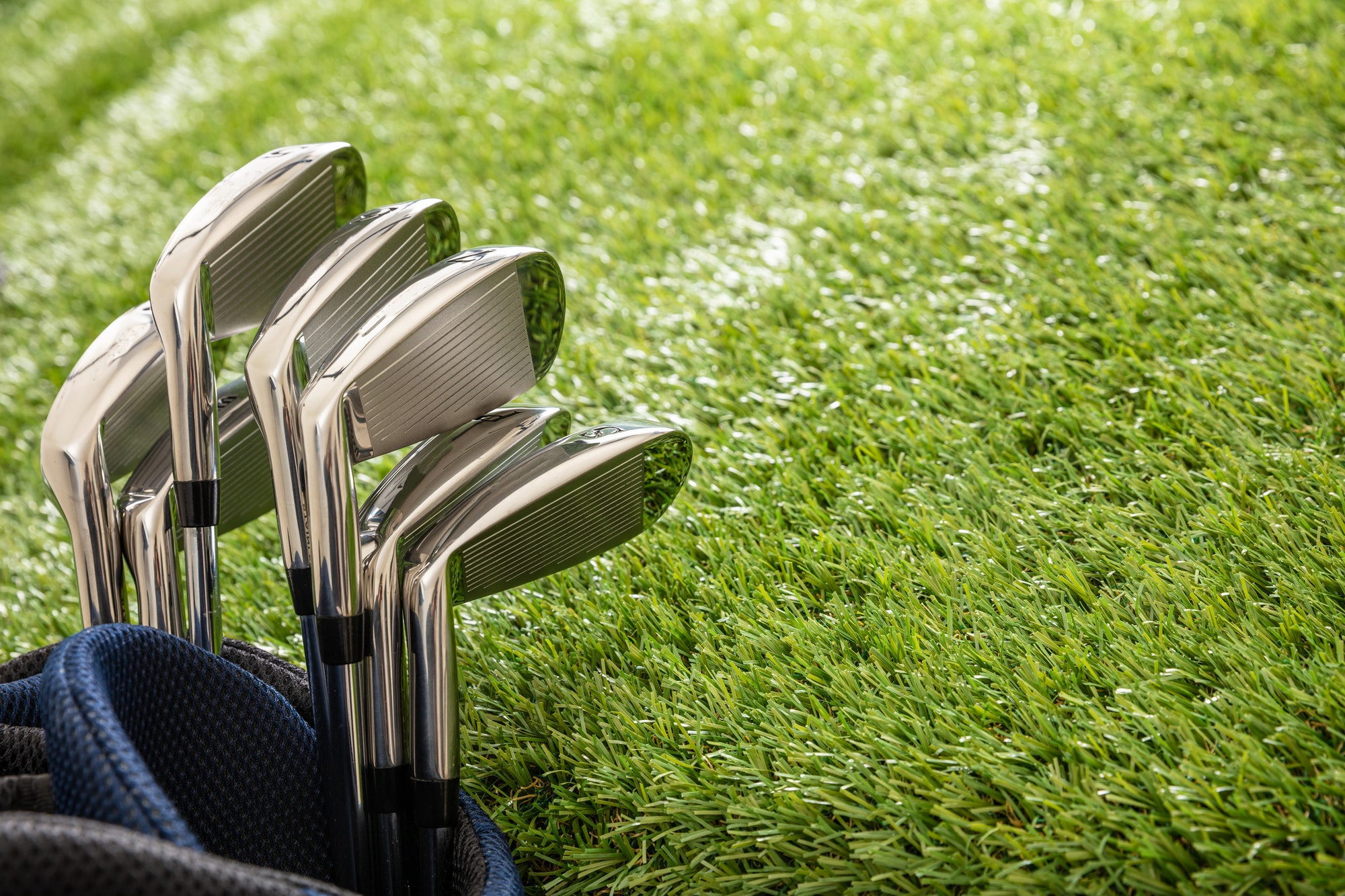 Golf clubs on green grass golf course, close up view.
