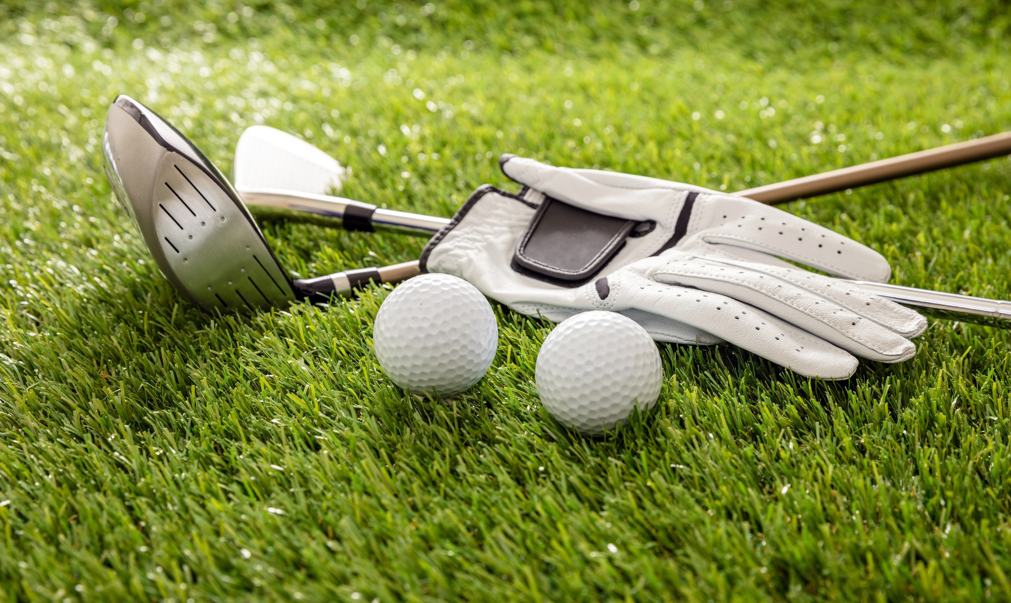 Golf equipment on green grass golf course, close up view.